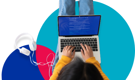 Young person typing on a laptop with headphones to the side